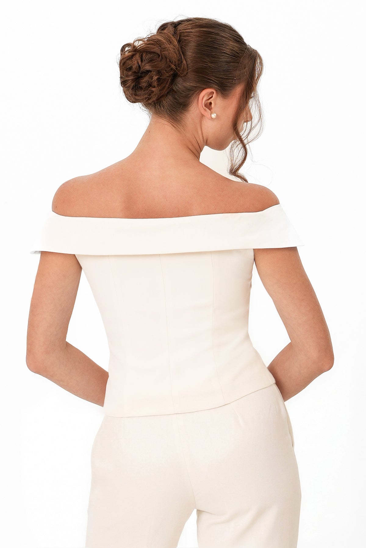 A woman shown from the back wearing an off-the-shoulder cream-colored top and matching pants against a plain white background.